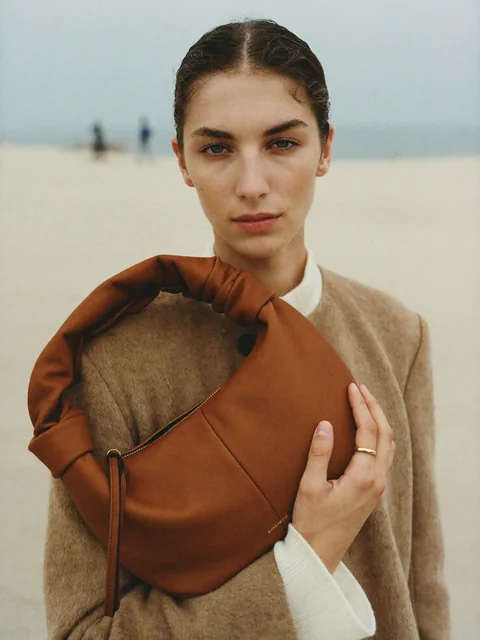 VEYRA Shoreline: a cognac leather bag held against the camel coat