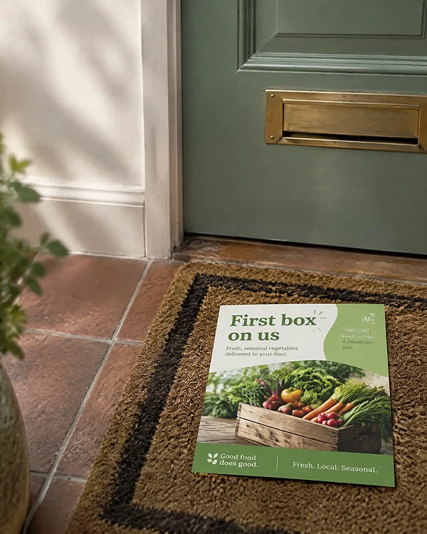 Green vegetable box postcard lying on a hallway doormat