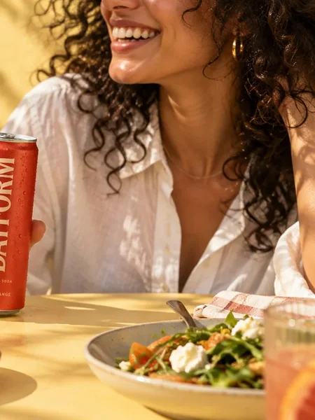 DAYFORM lifestyle ad, a woman at a sunny table with the can